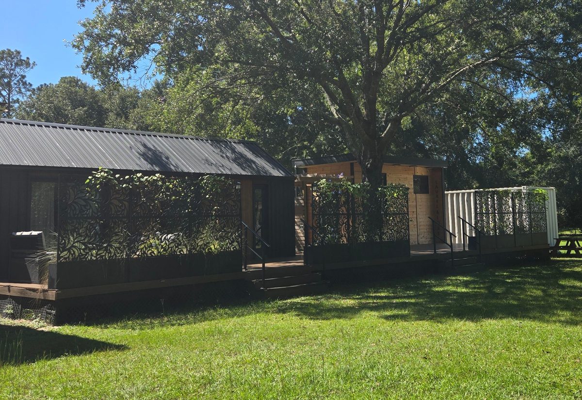 Laurel & Lore: a dark timber cabin with a deck, under a large oak, with an open lawn in front